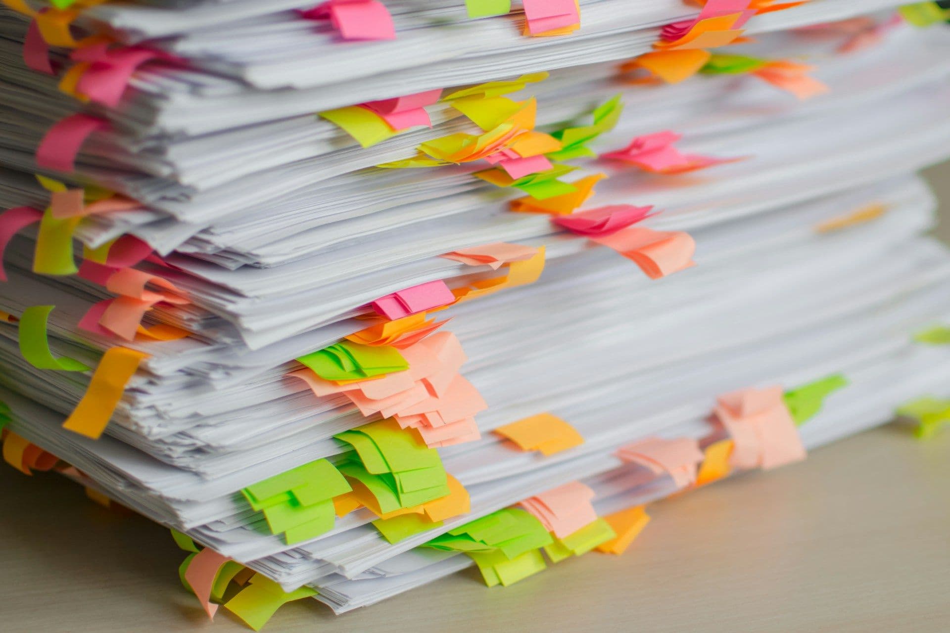 A stack of papers marked with colourful sticky tabs