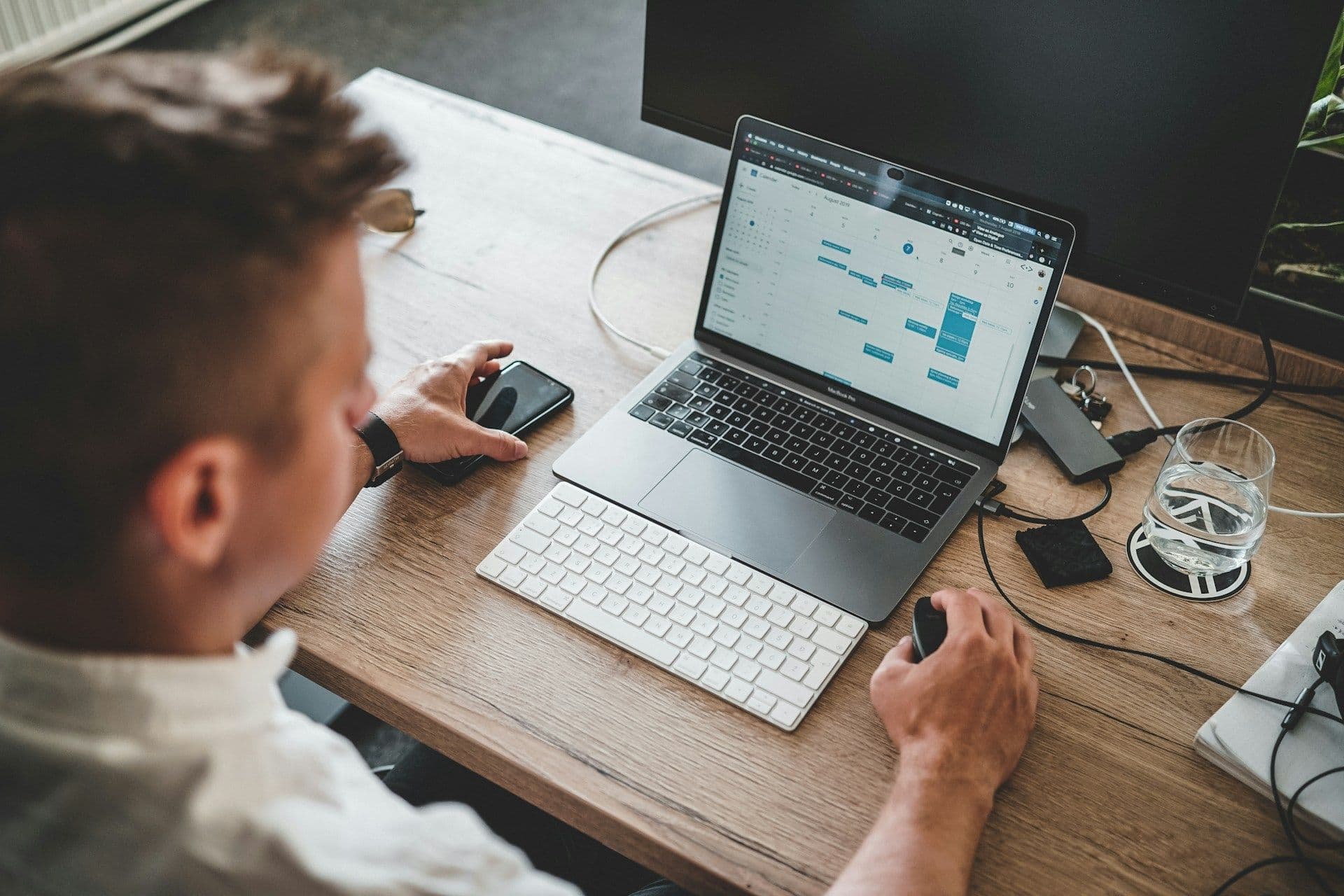 A person reviewing work on a laptop with a mouse and phone at hand