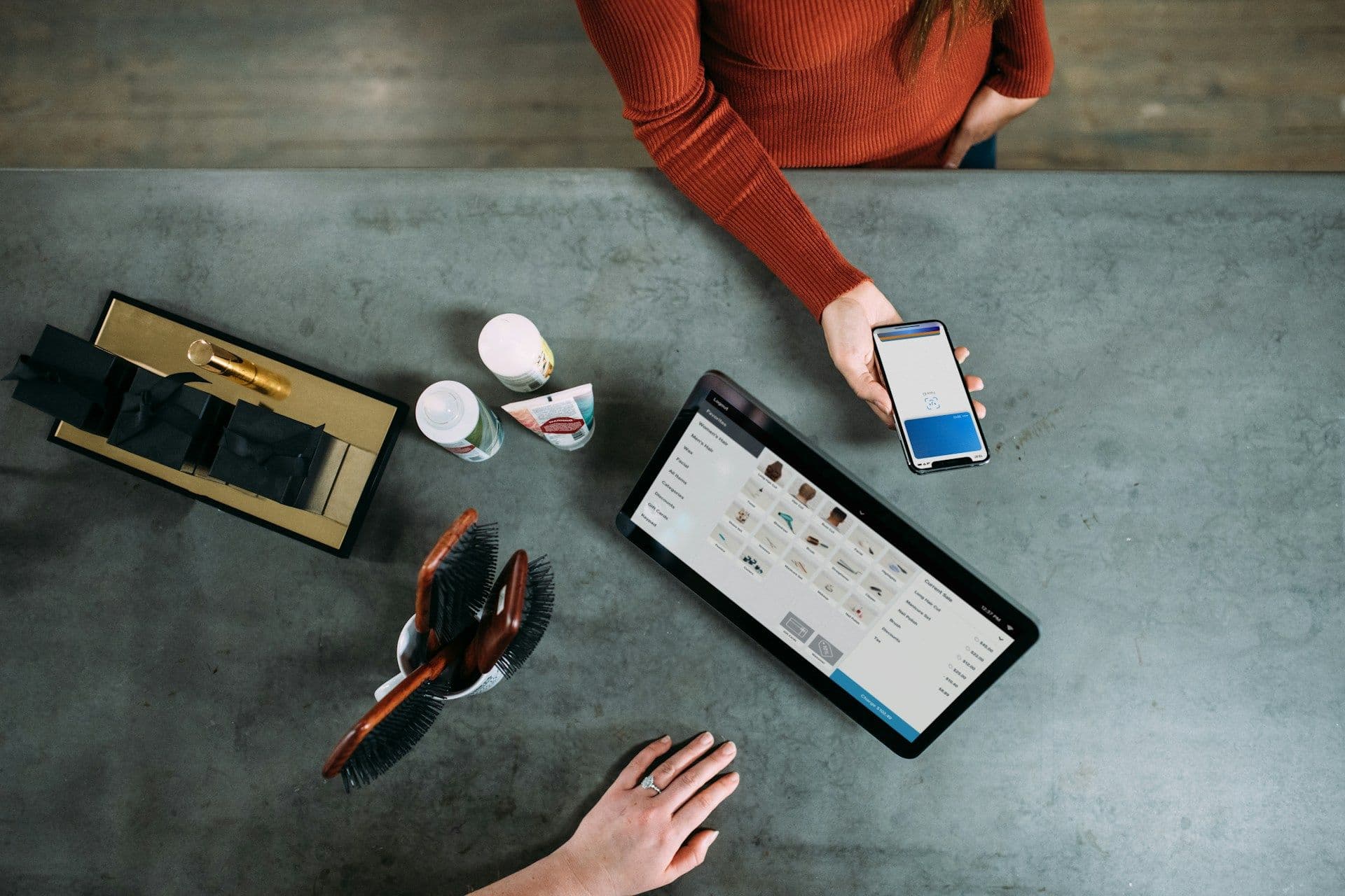 Smartphone tap-to-pay at a retail point-of-sale counter with a tablet product display